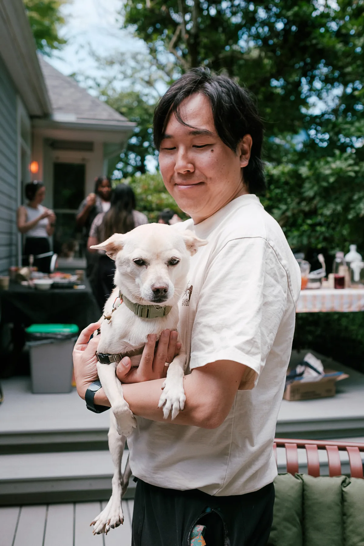 Parent holding a dog at a backyard gathering